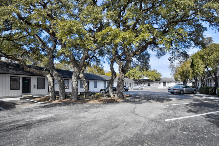 Charming residential complex with large shade trees, ample parking, and peaceful surroundings.