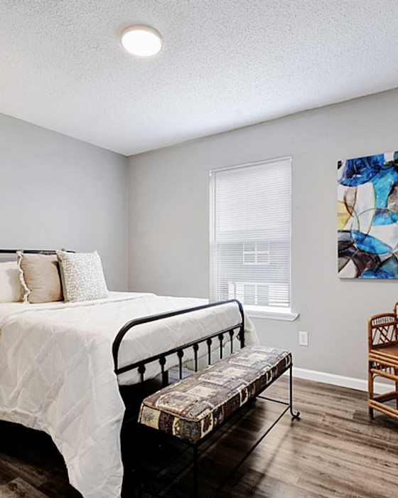 Inviting bedroom with modern decor, featuring cozy bed, stylish artwork, and abundant natural light, ideal for restful living.