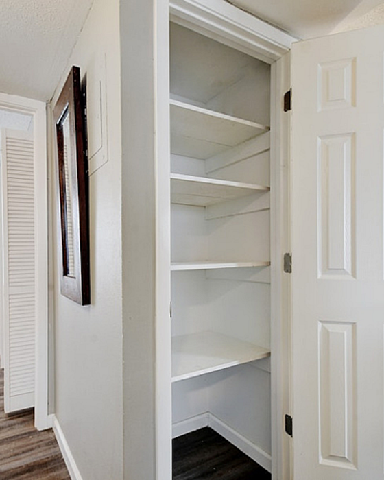 Spacious white pantry with multiple shelves and an open door, perfect for organized storage solutions in a modern home.