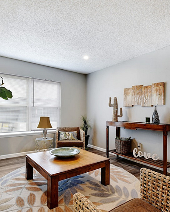 Bright and cozy living room with modern decor, featuring a wooden coffee table, elegant woven chairs, and a stylish accent wall.