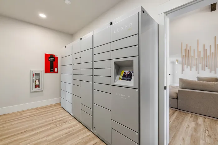 Modern apartment complex features a sleek Luxer package locker system near a cozy, stylish living area with wooden accents.