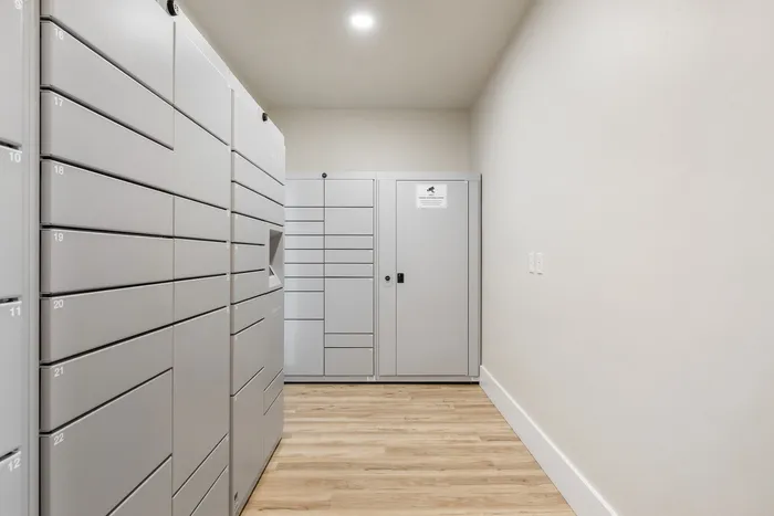 Modern parcel locker room with sleek gray lockers and warm wood flooring, providing secure and convenient package storage.