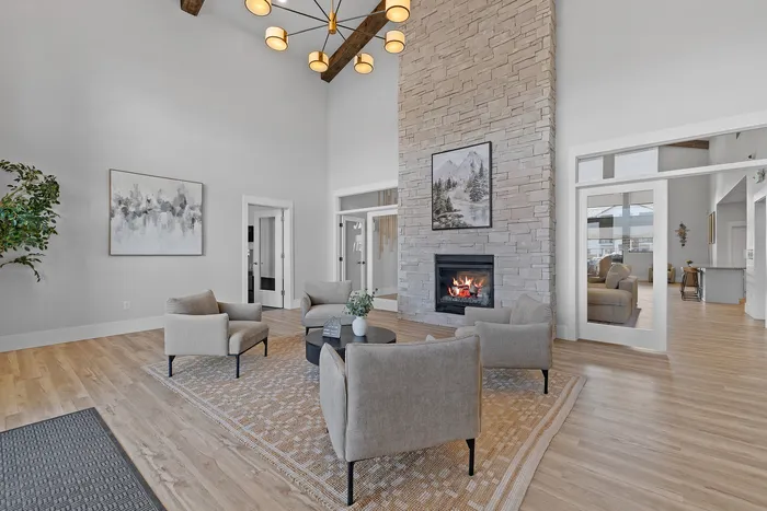 Elegant living room with a high ceiling, stylish chandelier, and cozy seating around a warm fireplace, enhancing a welcoming ambiance.