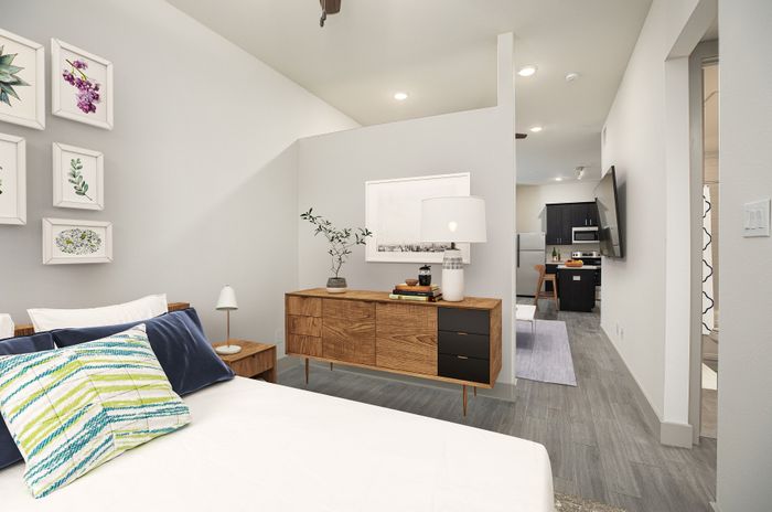 Chic apartment bedroom with modern decor, wooden furniture, and view into a contemporary kitchen.