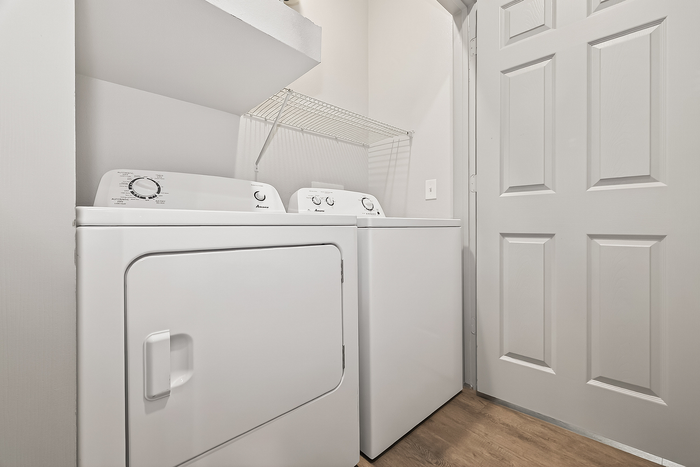 Modern laundry area featuring a sleek, white washer and dryer with convenient shelving above.