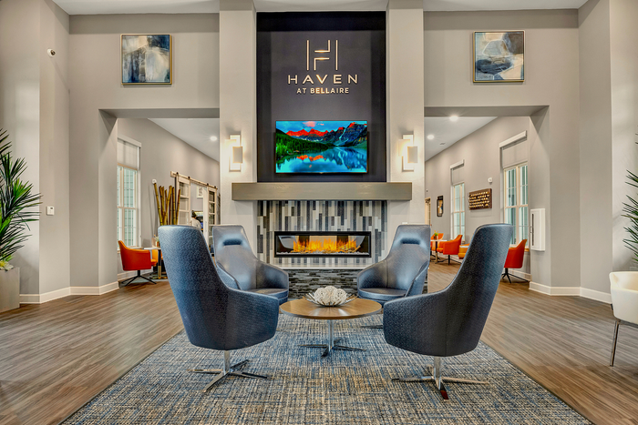 Elegant apartment lobby with modern decor, featuring stylish seating, a cozy fireplace, and vibrant artwork.