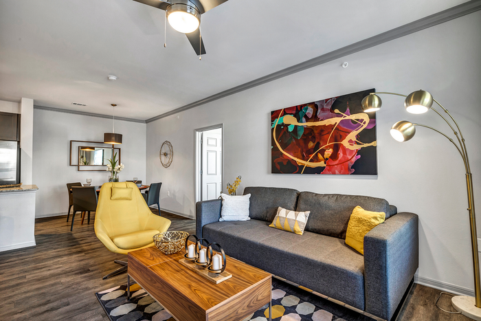 Modern living room with chic decor, featuring a sleek gray couch, a vibrant yellow chair, and a stylish wooden coffee table, all illuminated by a contemporary floor lamp.