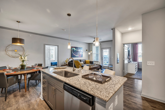Modern open-plan living area featuring a stylish kitchen with granite countertops, elegant dining space, and a cozy living room with contemporary decor.