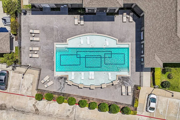 Aerial view of a stylish pool with modern geometric designs, surrounded by ample lounge chairs and shaded relaxation areas perfect for outdoor gatherings.