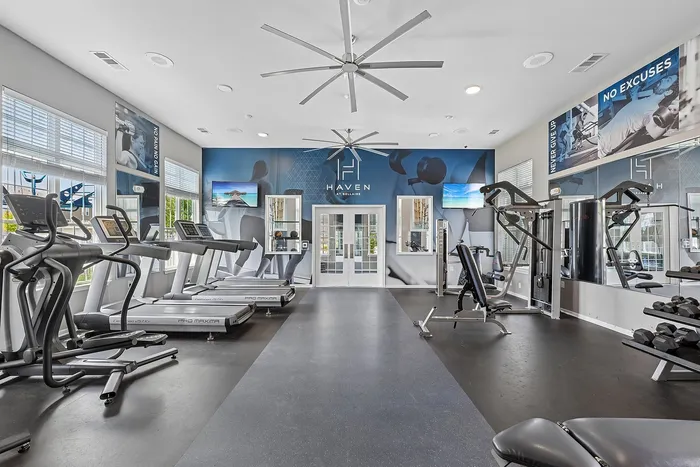 Bright and modern gym with state-of-the-art equipment, featuring treadmills, weight stations, and motivational decor at Haven Apartment Bellaire.
