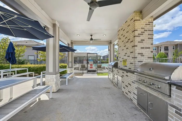 Inviting outdoor grill area with modern stainless steel barbecues and shaded seating, perfect for entertaining and relaxation.