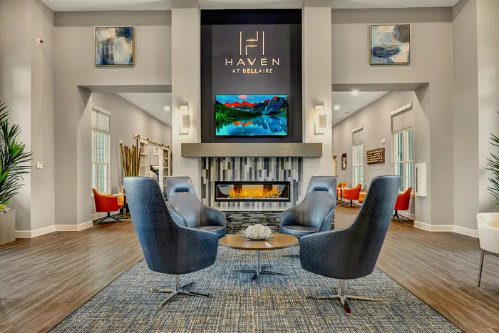 Luxurious apartment lobby showcasing stylish seating around a modern fireplace with elegant decor and vibrant artwork.