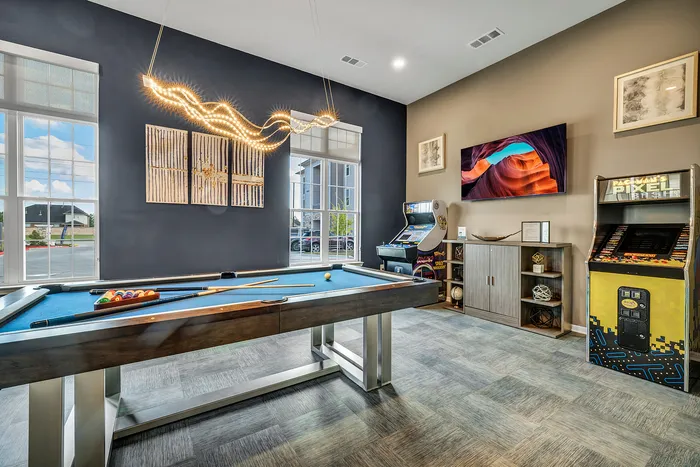Chic recreational room featuring a sleek pool table, eye-catching arcade games, and modern art under stylish lighting.