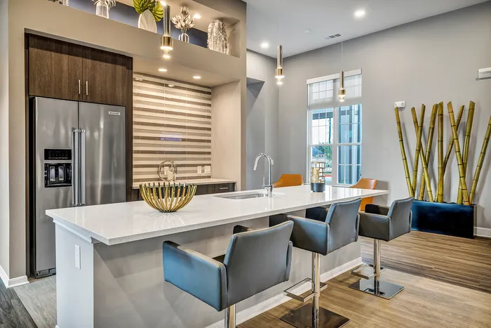 Modern kitchen with sleek design, featuring a large island with bar stools, stainless steel appliances, and ambient pendant lighting.