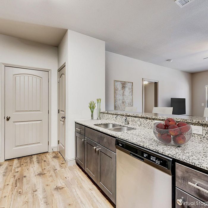 Modern kitchen with elegant granite countertops, stainless steel appliances, and stylish wood flooring, offering a sleek and inviting space.