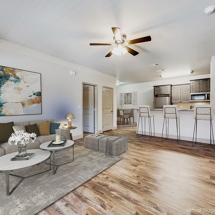 Modern open-concept living area with stylish decor, hardwood floors, and a sleek kitchen featuring bar seating and contemporary appliances.