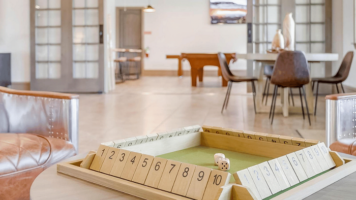 Modern open-concept living space featuring stylish furniture, an inviting sitting area, and a chic game setup on a wooden table.