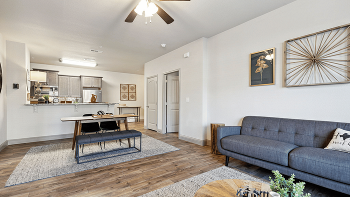 Chic living and dining area with an open-plan layout, featuring elegant wooden flooring, modern furniture, and a stylish gallery-style kitchen.