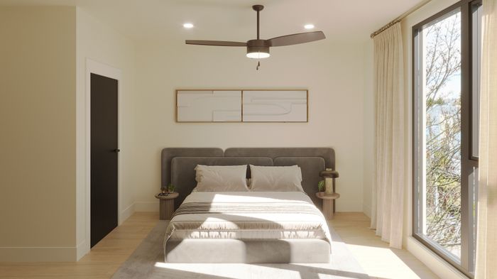 Bright, modern bedroom with a plush gray bed, sleek ceiling fan, and floor-to-ceiling window offering natural light and a serene view.