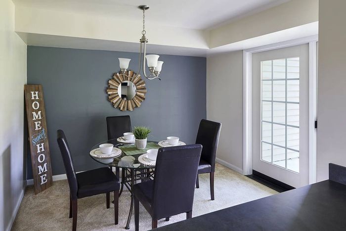 Millersville, PA, Apartments - Millers Crossing - Dining Area with Carpeted Flooring, Black Table and Chairs, Dark Accent Wall, Hanging Silver Chandelier, and French Door.