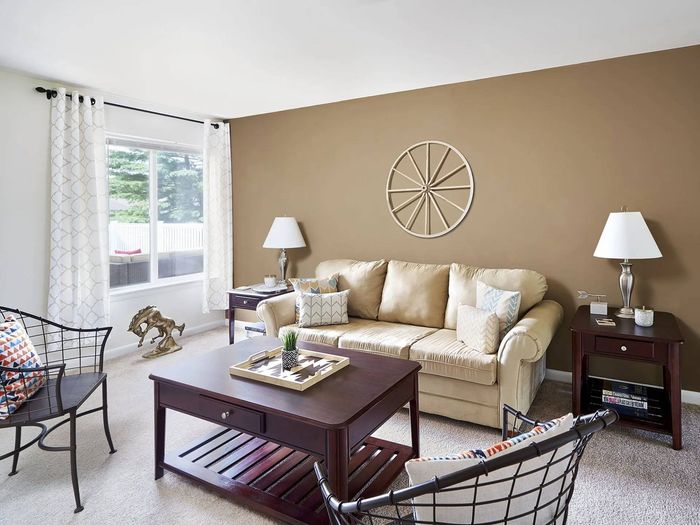 Apartments Near Millersville University - Millers Crossing Apartments - Living Room with Plush Carpet Flooring, a Large Window, and Stylish Decor