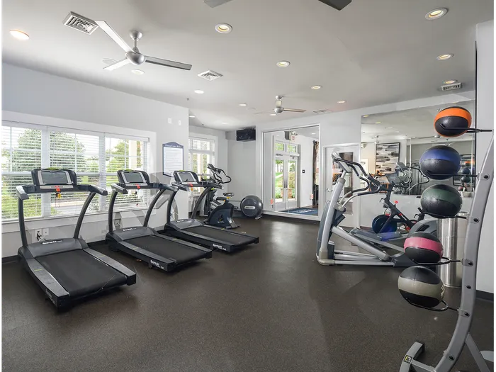 Plymouth Meeting, PA, Apartments - Plymouth Pointe - Fitness Center with Treadmills, Elliptical Machines, Exercise Balls, Mirrors, Ceiling Fans, and Windows.