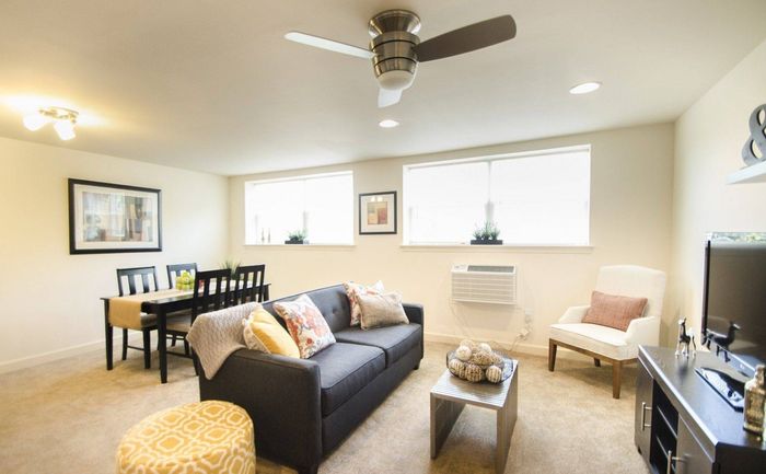Apartments in West Chester, PA for Rent - Audubon Pointe - Open Living Room With Plush Carpeting, Two Large Windows, and a Ceiling Fan