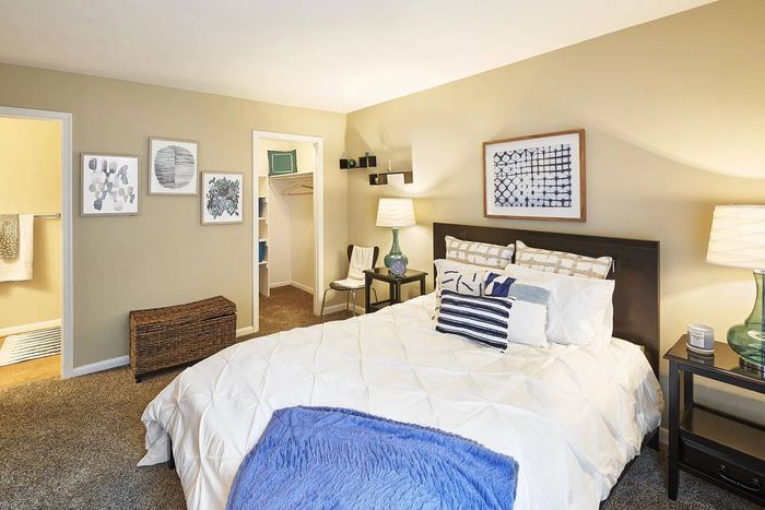 1, 2, & 3-BR Apartments In Frederick, MD - Willowdale Crossing - Spacious Bedroom With Carpet Flooring, Full-Sized Bed, Nightstands With Lamps, And A Walk-In Closet With Shelves