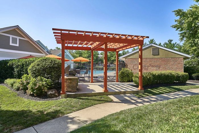 3-Bedroom Apartments in Frederick, MD - Willowdale Crossing - Outdoor Grill Station Under Pergola with View of Pool Area.