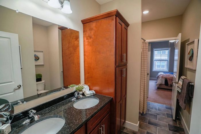 Apartments in Middletown, PA, for Rent - Woodland Hills - Bathroom with Tiled Flooring, Dual-Sink Vanity, Mirror, and Wooden Storage Cabinet.