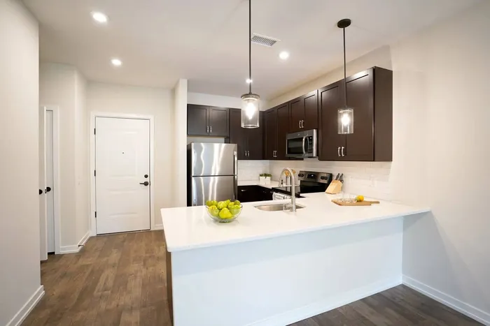 Doylestown PA Apartments for Rent - Butler Square - Kitchen with White Counters, Stainless Steel Appliances, Dark Wood Cabinetry, Light Tile Backsplash, and Large Kitchen Island