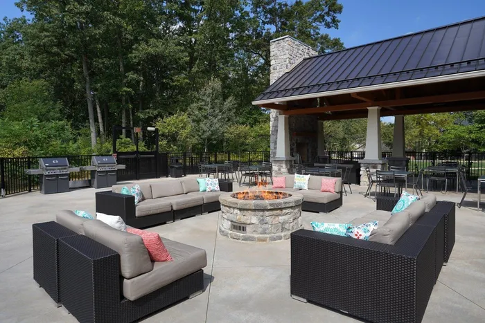 Apartments State College, PA - Toftrees - Outdoor Firepit with Grey-Cushioned Sofas, Pair of Grills, Tables, and Picnic Pavilion.