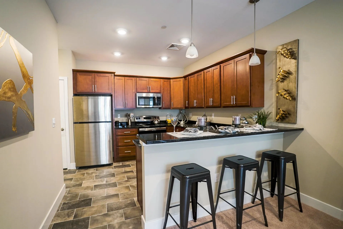 Pet Friendly Apartments in Middletown PA - Woodland Hills - A Bright And Spacious Kitchen With Tile Flooring, Dark Wood Cabinetry, Stainless Steel Appliances, And Bar Seating