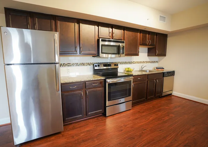 Dog-Friendly Apartments in West Chester - Market Street Flats - Kitchen with Wood-Style Flooring, Dark Cabinets, Granite-Style Countertops, and Stainless Steel Appliances