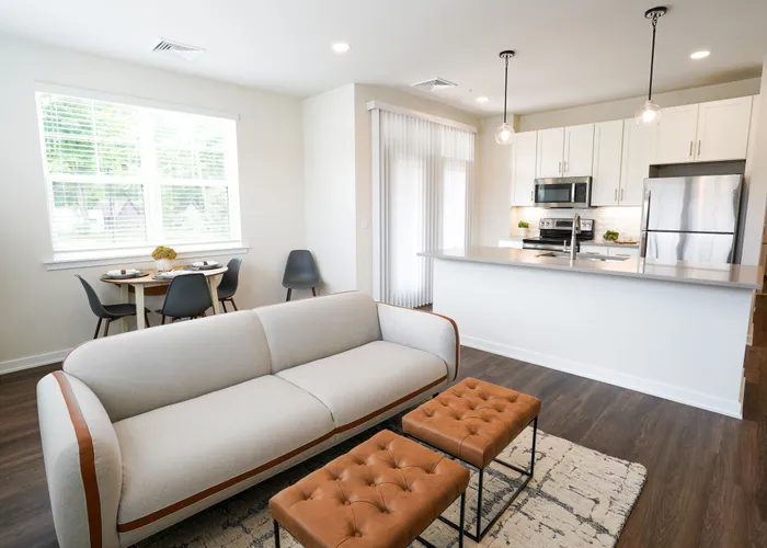 Pet-Friendly Apartments in Doylestown, PA - Butler Square - Open Living Area with Couch, Window, Area Rug, Chairs, and Access to Kitchen and Dining Area