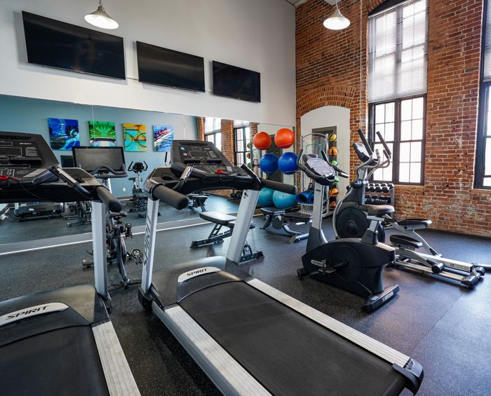 Allentown PA Apartments - The Mill - Fitness Center with Cardio Equipment. Free Weights, Mirrored Wall, Multiple TV Screens, and Large Windows