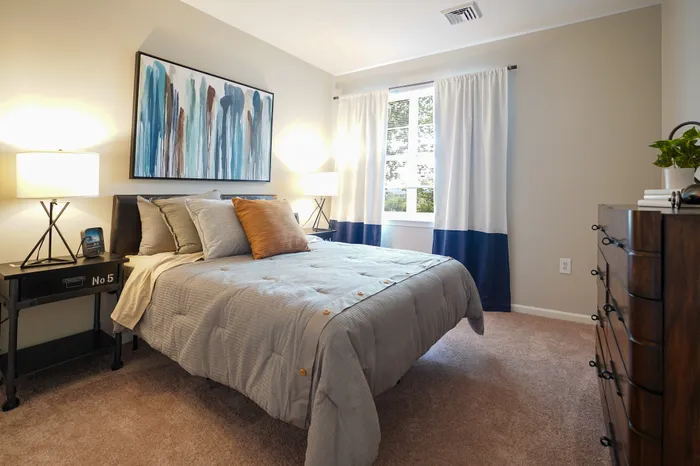 3-BR Apartments in Plymouth Meeting, PA - Plymouth Pointe - Furnished Bedroom with Plush Carpeted Flooring and a Window