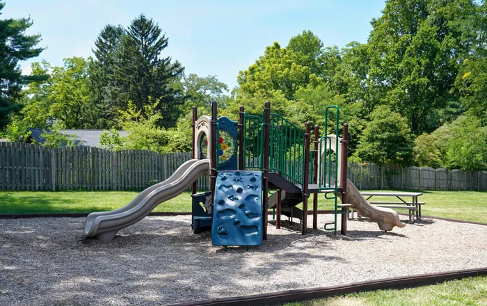 Apartments in West Chester for Rent - Goshen Terrace - Playground with Slides, Climbing Places, Woodchips, a Picnic Table, and a Fence