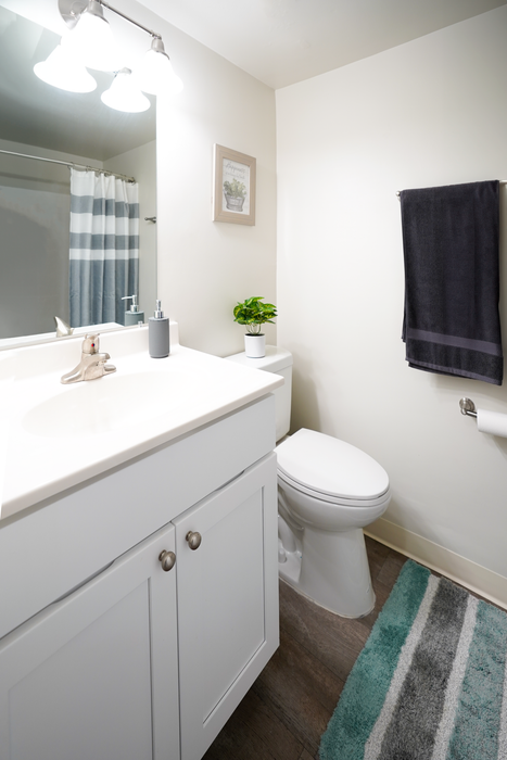 Upper Chichester, PA Apartments - Aston Glen - Bathroom with White Countertops, White Cabinetry, Wood-Style Flooring, and a Single Sink Vanity