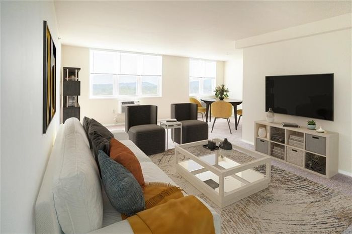 1-Bedroom Apartments in Allentown, PA - Regency - Living Room with Carpeted Flooring, Couch, Coffee Table, Armchairs, Storage Cabinet, TV, View of Dining Area, and Windows.