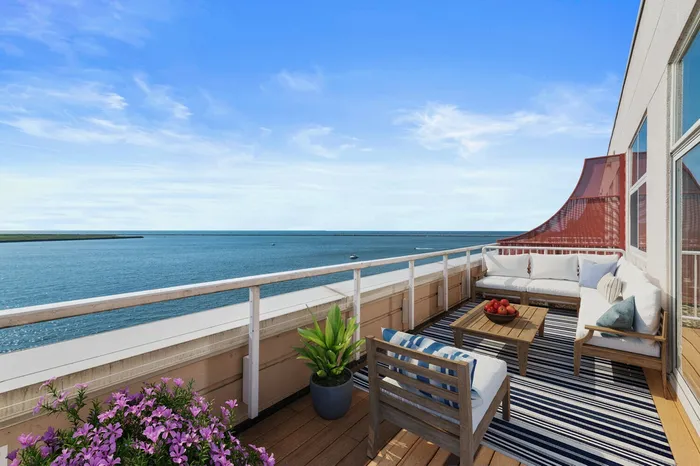One-Bedroom Apartments in Cleveland, OH - The Shoreline - Sundeck with Wood Flooring, Sectional Outdoor Sofa, Chair, Coffee Table, Potted Plants, and Expansive Lake Views.