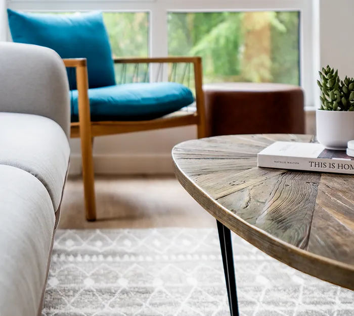Pet-Friendly Apartments In Lancaster, PA - 202 Queen Apartments - Living Room With Wood-Style Flooring, Area Rug, Couch, Armchair, Coffee Table, Oversized Windows, And Direct Access To The Kitchen