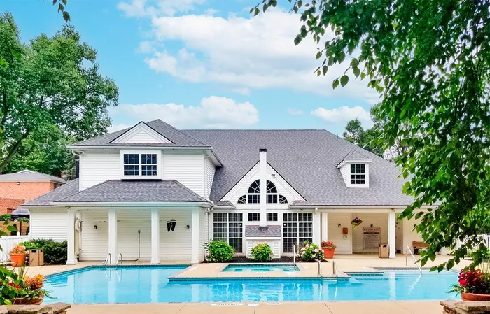 Sparkling outdoor swimming pool and hot tub with the clubhouse in the background at Village at Mayfield.
