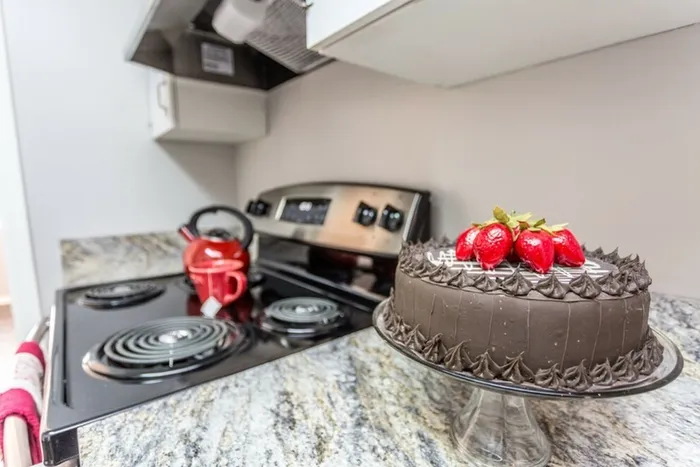 Close view of a chocolate cake with strawberries on a granite countertop.