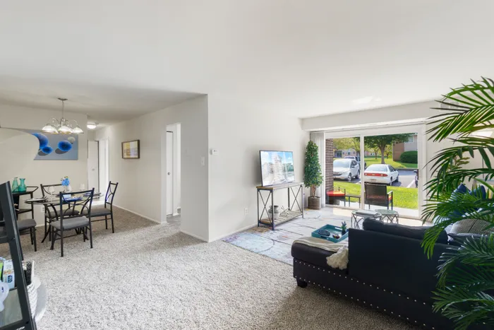 Comfortably furnished open-concept living and dining areas with a table, sectional, and TV.