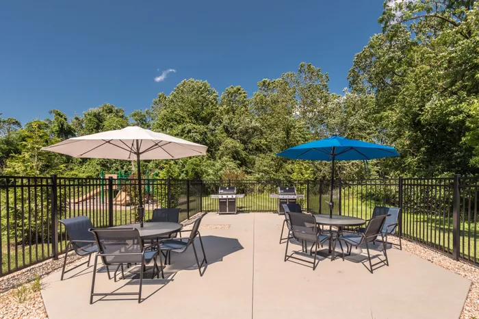 Outdoor community area with tables, chairs, and gas grills.