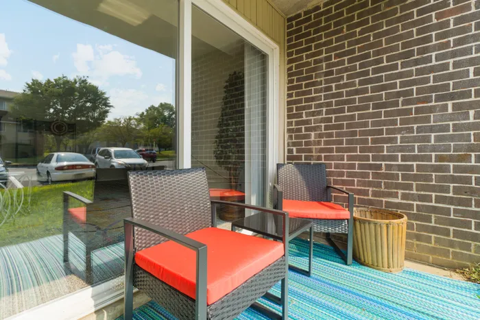 Private outdoor patio at Apartments at Bel Air in Bel Air, MD with two chairs and sliding glass doors.