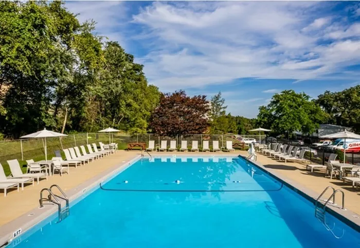 Two-Bedroom Apartments In Jefferson Hills, PA - Heritage Hills - Gated Sparkling Swimming Pool With Sundeck, Lounge Chairs, And Umbrellas, Next To Lots Of Greenery An Trees