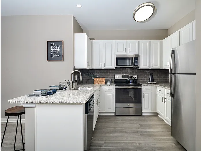 Dog-Friendly Apartments in Plymouth Meeting, PA - Plymouth Pointe - Kitchen with Stainless Steel Appliances, White Cabinets with Grey-Granite Countertops, and Wood-Style Plank Flooring
