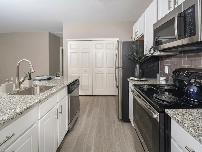 Dog-Friendly Apartments in Plymouth Meeting, PA - Plymouth Pointe - Kitchen with Stainless Steel Appliances, White Cabinets with Grey-Granite Countertops, and Wood-Style Plank Flooring